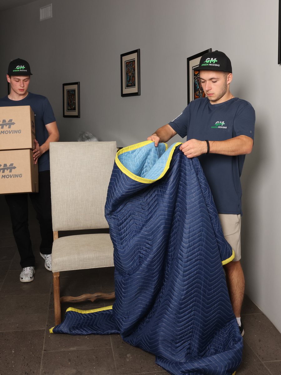 Movers wrapping an armchair in a moving blanket